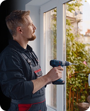 Працівник компанії Вікно PROF, який виконує роботу по регулюванню віконної дверці.